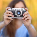 Photographe tenant un appareil avec un arrière-plan doux et flou