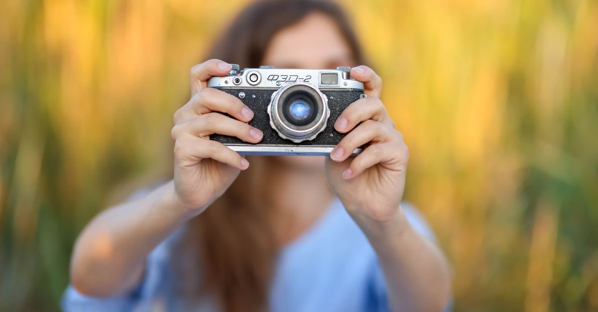 Photographe tenant un appareil avec un arrière-plan doux et flou