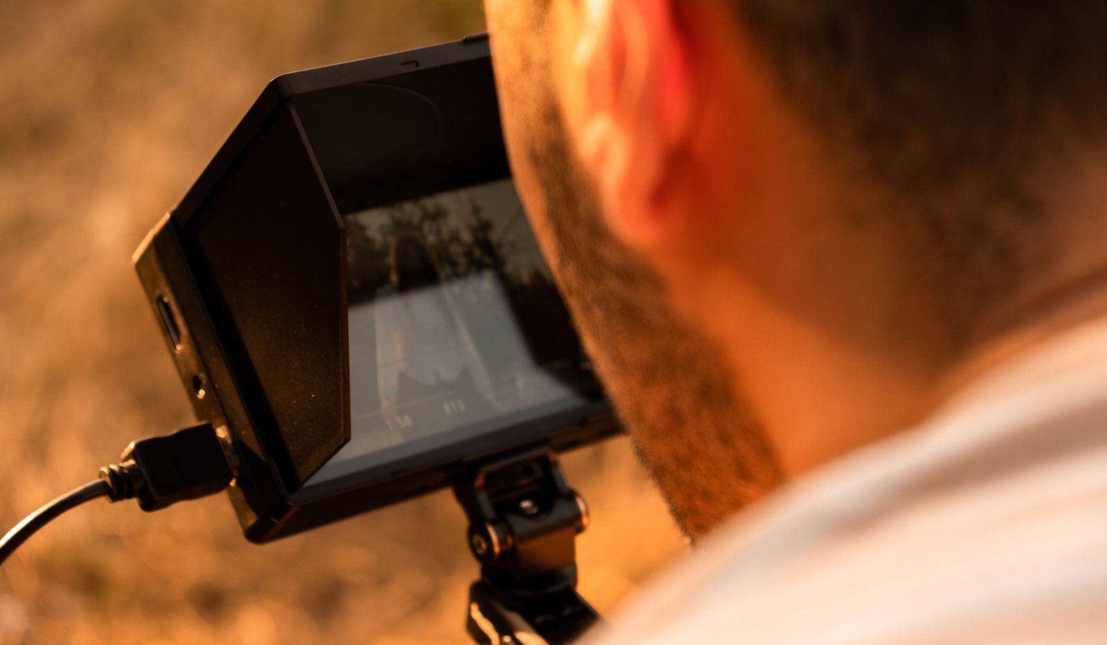 Photographe ajustant l’écran de son appareil photo dans une lumière chaude.