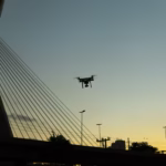 Drone en vol près d’un pont urbain, illustration des règles de vol en agglomération